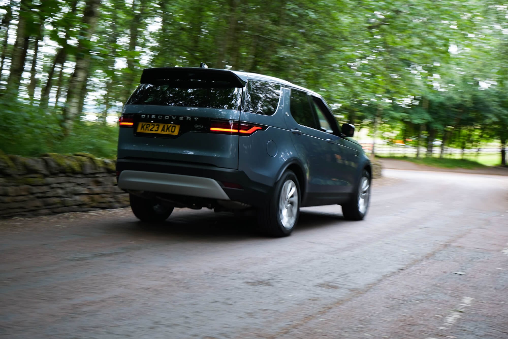 Rear view of a Land Rover Discovery driving through woodland
