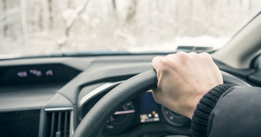 Image of hand on steering wheel driving in winter