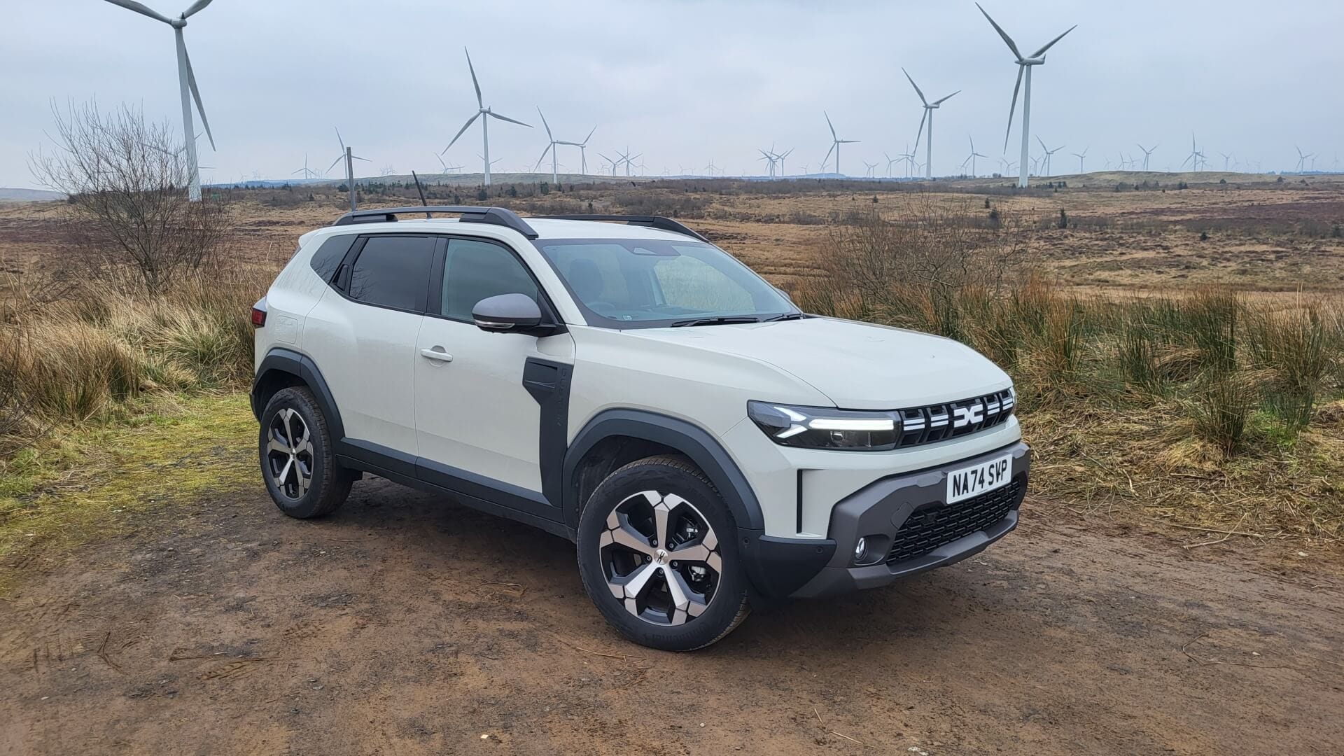 Image of the 2024 Dacia Duster Journey parked on a wind farm.