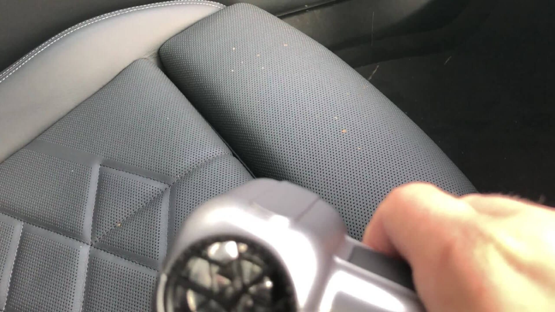 Image of Dylan cleaning a car seat with crumbs on it, using the Wolfbox air duster.